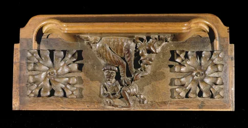 Une miséricorde représentant une petite figure coiffée attaquée par un monstre, New College Chapel, Oxford, fin du 14ème siècle