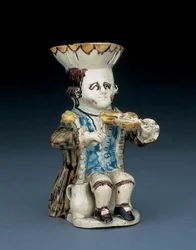 Pichet Toby du violoneux, son chapeau au bord festonné brun et jaune, ses cheveux bruns incisés et noués en queue avec une rosette blanche, vêtu d