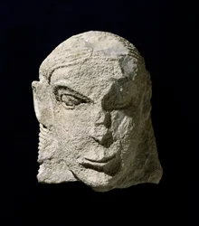 Civilisation étrusque : tête de femme en calcaire. 650 av. J.-C. environ. Du tumulus de la Pietrera di Vetulonia. Florence, Museo Archeologico