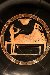 Coupe : symposiaste et jeune esclave jouant le double aulos (Céramique à figures rouges,)