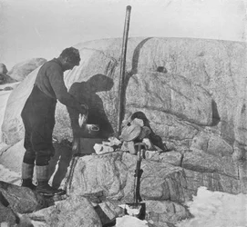 Forde cuisinant du phoque sur le poêle à graisse au Cap Roberts, vers 1911, 1913