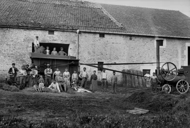 Travailleurs agricoles et la presse attachant des bottes de foin sur une ferme près de Bourmont en Haute-Marne, vers 1890 (photographie, Collection Ducos)