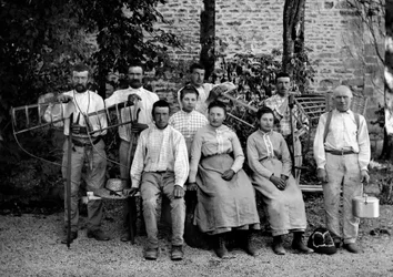 Travailleurs agricoles et leurs outils, faux, râteau-étrier, panier de tressage et récipient pour la collecte, dans une ferme près de Bourmont en Haute-Marne, vers 1890. Photographie. Collection Ducos
