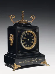 Une pendule de cheminée en pierre noire, avec décoration incisée, avec pieds, ornements et accessoires en laiton doré, par Jausions de Pau, France, vers 1876-78