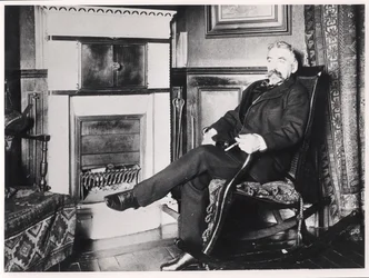 Stéphane Mallarmé (1842-98) assis près de la cheminée chez lui, rue de Rome, Paris