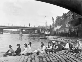 Enfants sur la chaussée pavée sous le pont de Southwark, Londres, vers 1930