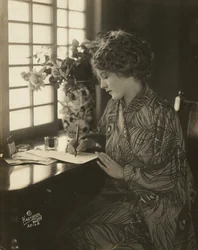 Mary Pickford, portant un kimono, écrivant à un bureau, c.1918