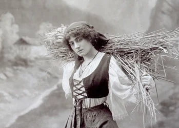 Jeune femme en tenue traditionnelle portant un fagot de paille