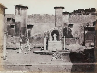 Vue partielle du jardin surélevé de la Maison de Marcus Lucretius à Pompéi, décoré de statues en marbre et de hermès. Au centre, une fontaine avec une niche. En arrière-plan, des fragments de peintures murales