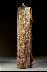 Bouclier rectangulaire incurvé Sepik, le devant avec une bande centrale de cinq masques, chacun avec une fibre dans le septum percé, dans un panneau de zigzags sculptés (bois, plumes et raphia)