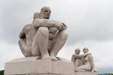 Sculptures en granit de deux hommes nus assis dos à dos ; sculpture de deux femmes au dos d