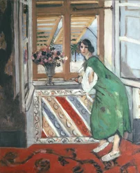 Intérieur à Nice : jeune femme en robe verte accoudée à la fenêtre