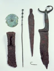 De haut en bas : couteau, pointe de lance, hameçon, épingle à vêtement, disque de ceinture et hache, tous trouvés dans des tombes masculines à Hallstatt, âge du fer