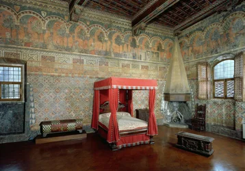 Salle de la Castellana di Vergi montrant les murs et la frise fresqués représentant une romance médiévale française