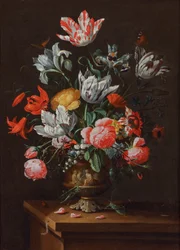 Tulipes et autres fleurs dans un vase baroque en grès peint sur un rebord en bois