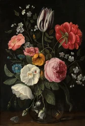 Roses, tulipe, pivoine, fleur de cerisier et centaurée dans un vase en verre sur un rebord.