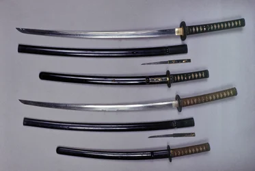 En haut : un katana, épée japonaise et son fourreau, wakizashi, épée courte japonaise dans son fourreau, petit poignard Kokatawa rangé dans le même fourreau. tous trois sont du 18e siècle. les inférieurs sont du 17e siècle