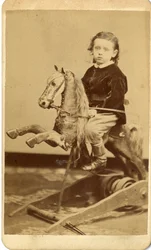 Jeune garçon avec fouet sur cheval à bascule
