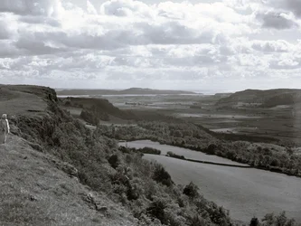 Une dame se tient sur une colline et regarde le paysage de Scout Scar.
