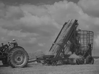Tracteur tirant un cadre mobile et chargement du foin dans celui-ci