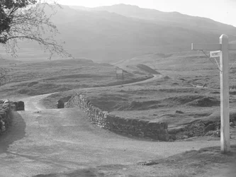 Vue de la route passant au-dessus du col de Hardknott avec un panneau indiquant la direction de Hardknott