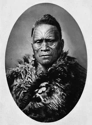 Un chef maori avec un visage tatoué de manière élaborée et un manteau de temps, 1902