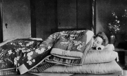 Saki, la gouvernante dort sur un matelas avec un oreiller dur sous un kimono matelassé, vers 1900, 1921