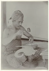Homme javanais fabriquant une image ressemblant à une figure humaine avec un marteau et des instruments