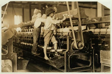 Petits garçons grimpant sur un cadre de filature pour réparer des fils cassés et remplacer des bobines vides à Bibb Mill, Macon, Géorgie, 1909