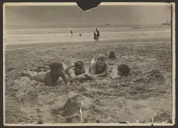 [Enfants allongés dans le sable à la plage]