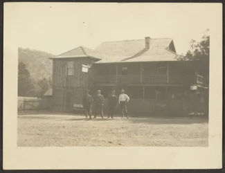 [Quatre hommes devant un bâtiment en bois]