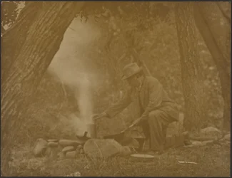[Un homme en train de cuisiner sur un feu de camp dans les bois]