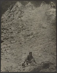 [Un homme accroupi dans un paysage rocheux]