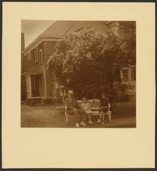 [Homme et jeunes filles sur un banc devant une maison]
