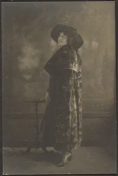 [Portrait de femme en manteau long devant la tapisserie]