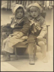 [Deux enfants partageant la même chaise]