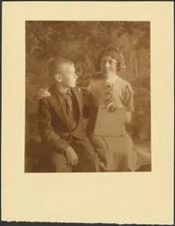 [Une femme et un jeune homme assis devant une tapisserie]