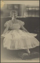 [Femme en robe de mousseline assise sur un sofa]