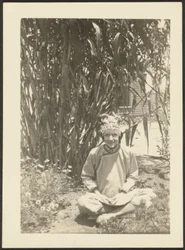 [Femme en costume assise dans un jardin]