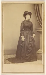 [Femme non identifiée portant un chapeau et une longue robe sombre.]
