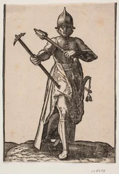 Soldat casqué debout, vu de face; dans la main droite un marteau de guerre, dans la main gauche une massue, la jambe et le pied arrière tordus par rapport à l