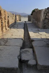 Site archéologique minoen de Phaistos. Large corridor avec un conduit de drainage derrière la porte de l
