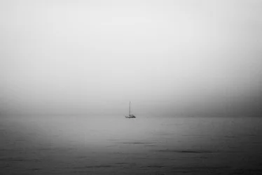 Un voilier solitaire dans le brouillard