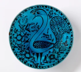 Un plat en poterie persane du 19ème siècle représentant un paon sur un fond turquoise