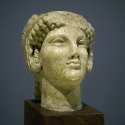 Tête de jeune fille (Korè), sculpture de la période hellénistique romaine (3e-2e siècle après notre ère), visage très expressif, pommettes saillantes vers l