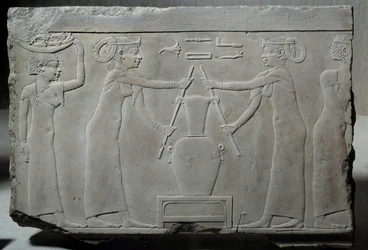 Antiquité égyptienne : bas-relief en calcaire représentant des femmes pressant des fleurs de lys pour extraire l