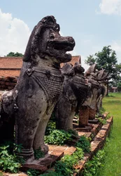 Figures de gardiens en pierre ressemblant à des lions autour de la base du stupa