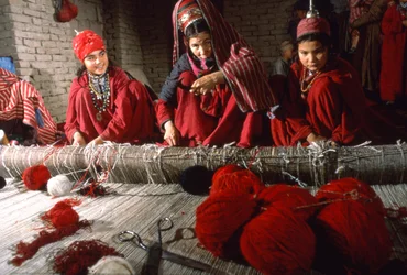Femmes tisserandes turkmènes coupant les nœuds dans la chaîne d
