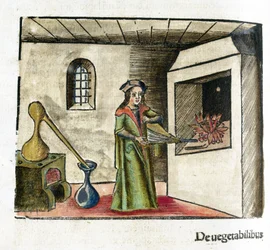 Alchimie XVIe siècle: un alchimiste au travail, activant un soufflet devant la cheminée de son atelier, derrière lui, un poêle et un alambic