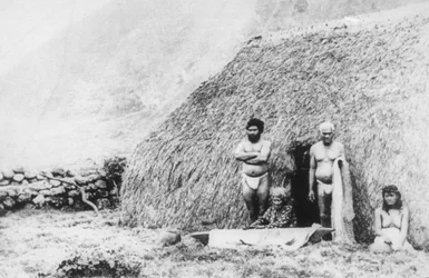 Une vieille femme battant du tapa devant une maison en herbe pili, Kalaupapa, Hawaï, 19ème siècle